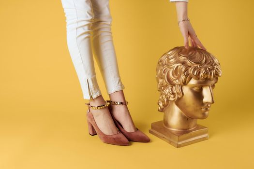 Golden head sculpture female legs fashion yellow background. High quality photo