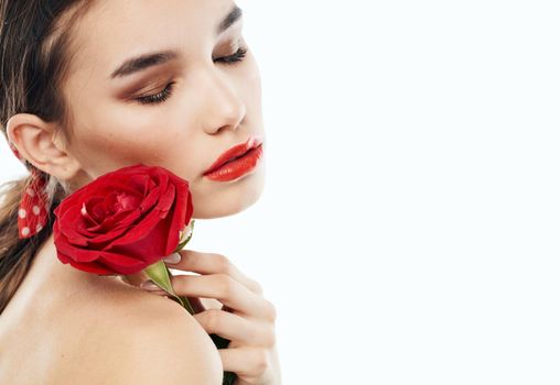 Young lady with bare shoulders and and a red flower near her face. High quality photo