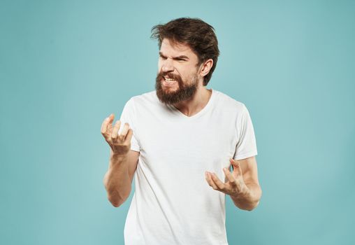 Cute man on a blue background gestures with his hands stress Scream irritability outrage. High quality photo