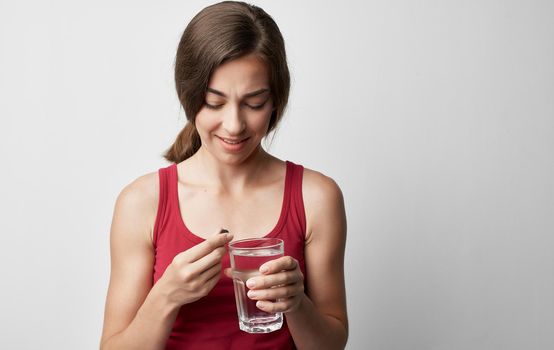 makeup woman in red t-shirt holds glass of water pill medicine health problems. High quality photo
