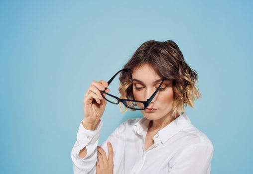 Fashionable woman curly hair short haired glasses and white shirt blue background. High quality photo