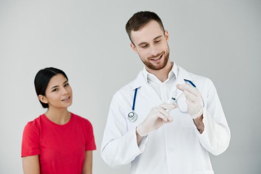 male doctor in a white coat next to the patient holds an injection in his hands. High quality photo