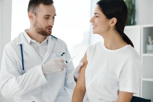 doctor in protective gloves injects a woman's shoulder from covid-19 vaccination. High quality photo