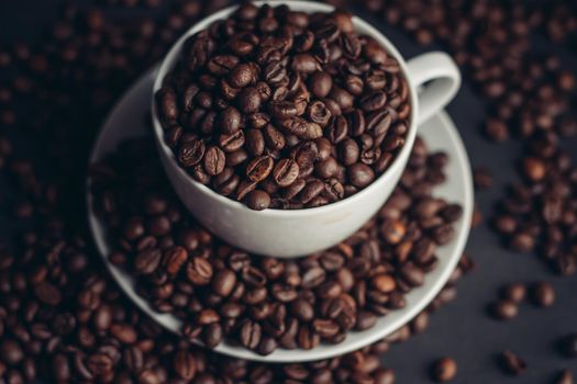 coffee beans in a cup and white saucers gray background close-up. High quality photo