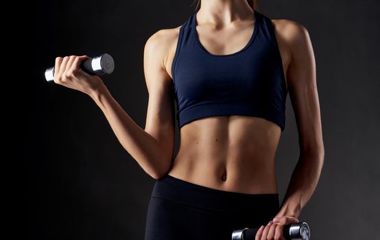 sportswoman in top on dark background cropped view fitness slim figure. High quality photo