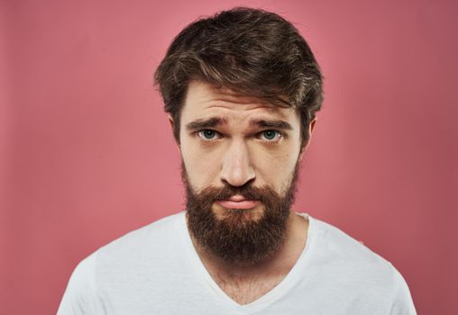 Man with a beard on a pink background sad face emotions model. High quality photo