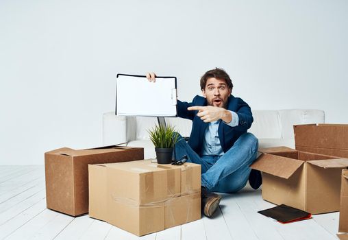 Business man sitting on the floor with boxes unpacking documents to the office manager. High quality photo