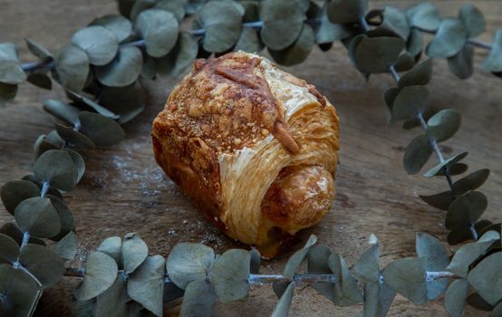Baked croissant sausage and Dried flowers on old rustic wooden table. Bakery and dessert concept, Selective focus.