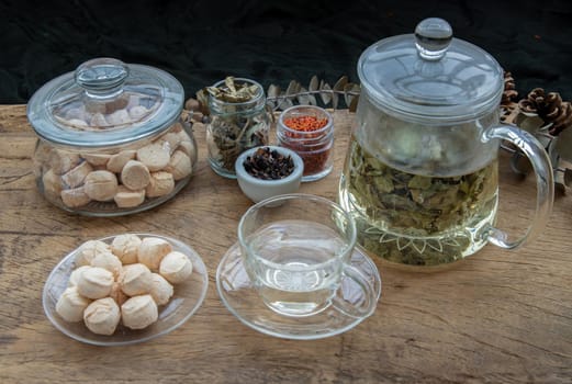 Morning refreshing with herbal tea which is served with Khanom Ping (Thai traditional dessert). The desserts is served on rustic wooden background. Thai style high tea, Selective focus.