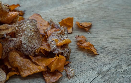 Mixed thai sweets made from sliced sweet potato coated with sugar (Potato chip) on rustic wooden background. Copy space, Selective focus.