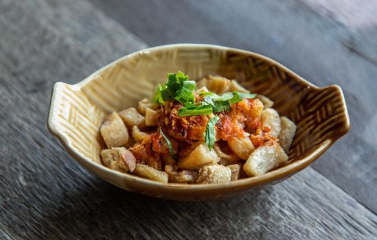 Pork Crackling from lard or Stir-Fried Pork Crackle seasoning with spicy-sweet dipping sauce in ceramic bowl. It is a delicious appetizer. Selective focus.