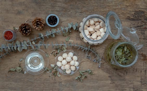 Morning refreshing with herbal tea which is served with Khanom Ping (Thai traditional dessert). The desserts is served on rustic wooden background. Thai style high tea, Selective focus.
