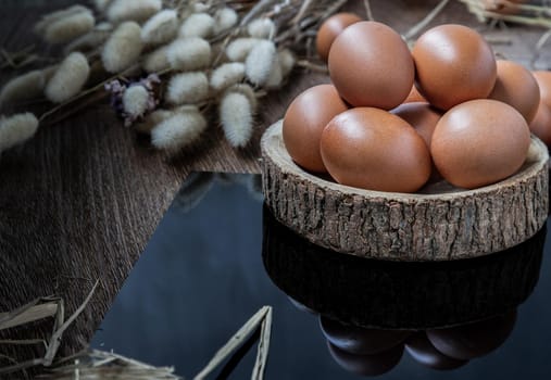 Fresh chicken eggs (Hen eggs) placed on small timber and Dried flowers on Black table. Fresh eggs from the farmer, Natural organic healthy food concept, Copy space, Selective focus.