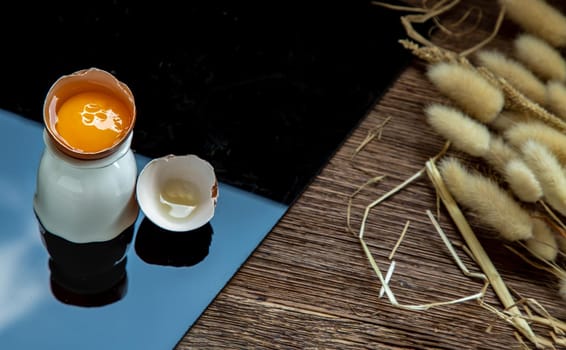 Broken chicken egg and Dried flowers on table. Copy space, Selective focus.