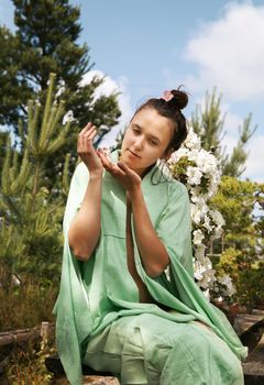 Japanese Garden. Young beautiful woman dressed in Japanese kimono at the garden enjoying the beauty of nature and blooming flowers