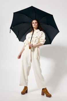 fashionable woman in white jumpsuit open full length umbrella fashion boots. High quality photo