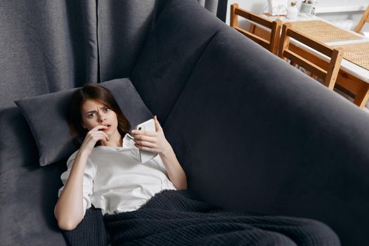 woman indoors lies on the couch with a mobile phone in her hand top view. High quality photo