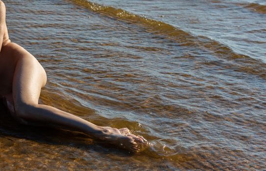 Beautiful girl outdoors enjoying nature. Young naked woman with scarlet dreadlocks enjoys the sea on the coast