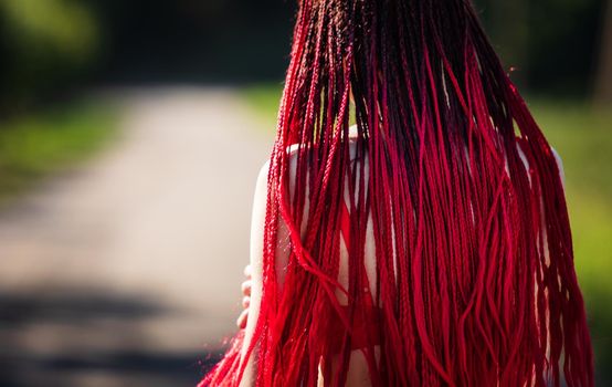 Beautiful girl outdoors enjoying nature. Seminude girl with scarlet dreadlocks in a red bathing suit sunbathes on the beach