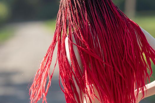 Beautiful girl outdoors enjoying nature. Seminude girl with scarlet dreadlocks in a red bathing suit sunbathes on the beach