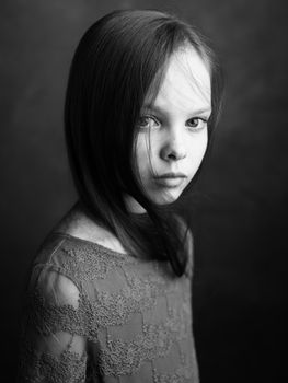 Portrait of a little girl in a dress on a dark gray background photograph cropped side view. High quality photo