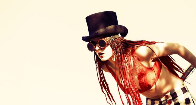 Glamorous girl with scarlet dreadlocks, a red swimsuit, black hat and welding glasses poses on the blue sky background. Free space for your text