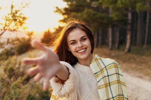 happy woman stretches her hand forward on nature near green bushes. High quality photo