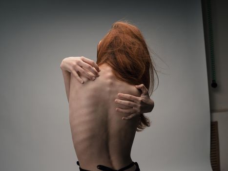A thin woman touches herself behind her back with her hands with emotion model. High quality photo