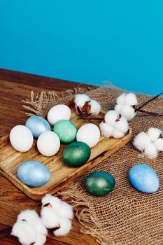 painted easter eggs on wooden board verbena flowers holiday blue background. High quality photo