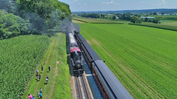 Aerial View of An Antique Restored Steam Locomotive Blowing Smoke and Steam Traveling Thru Farmlands and Countryside on a Sunny Summer Day