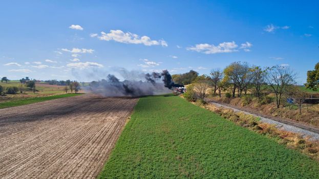 Aerial View of An Antique Restored Steam Locomotive Blowing Smoke and Steam Traveling Thru Farmlands and Countryside on a Sunny Summer Day