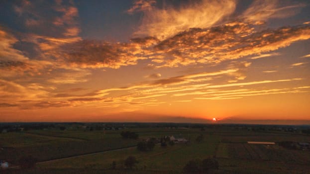 An Aerial View of a Sunset over Green Farm Lands with a Reddish Sky
