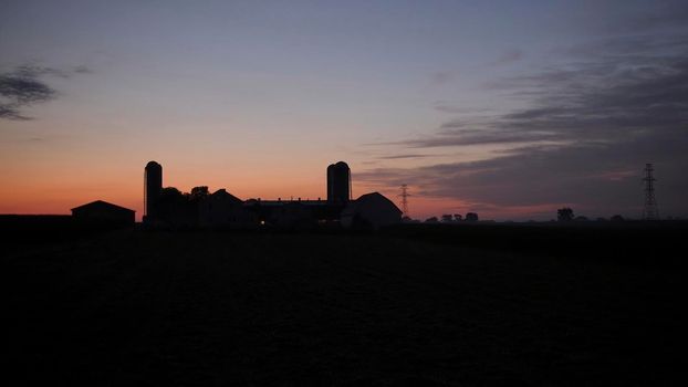 View of a Sunrise Looking over an Amish Farm with Farm House Barn and Silos