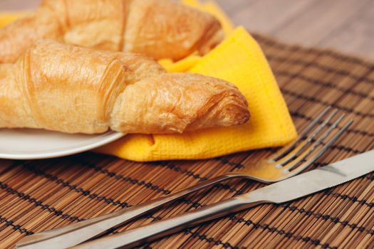 crispy croissants on a plate kitchen utensils for breakfast meal dessert. High quality photo