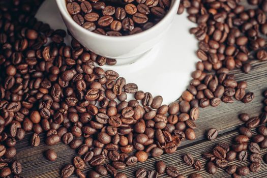 coffee beans on a wooden background and a cup on a saucer close-up macro photography. High quality photo