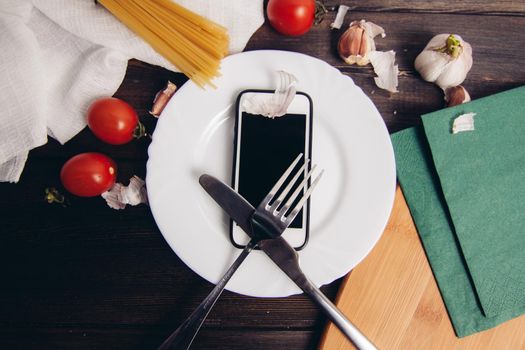 mobile phone plate knife with fork diet food pasta cherry tomatoes. High quality photo