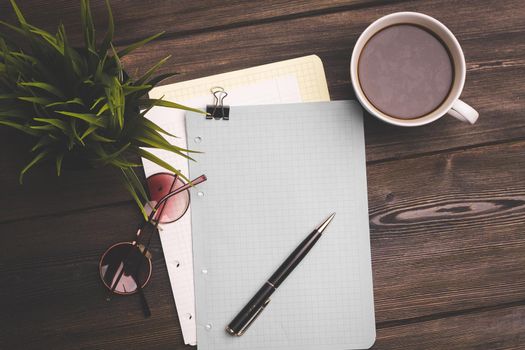 notebook and pen on a wooden table coffee cup flower in a pot top view. High quality photo