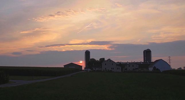 View of a Sunrise Looking over an Amish Farm with Farm House Barn and Silos