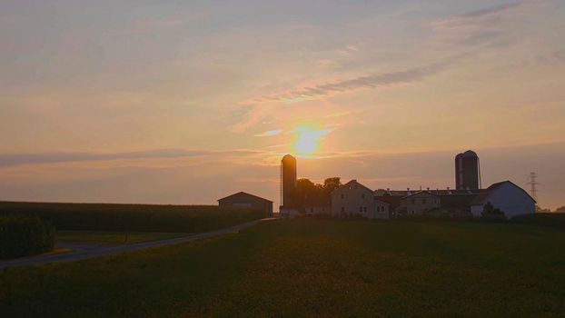 View of a Sunrise Looking over an Amish Farm with Farm House Barn and Silos