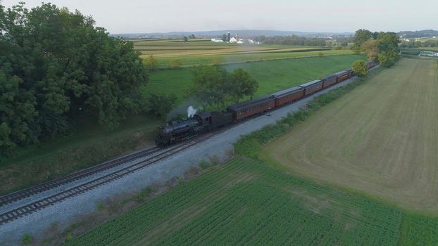 Aerial View of An Antique Restored Steam Locomotive Blowing Smoke and Steam Traveling Thru Farmlands and Countryside on a Sunny Summer Day