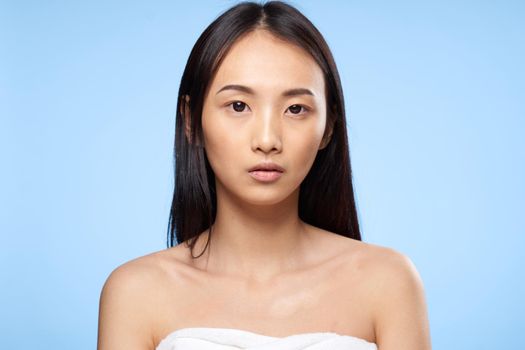 woman of asian appearance with bare shoulders clear skin care blue background. High quality photo