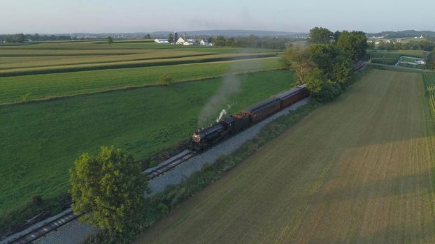 Aerial View of An Antique Restored Steam Locomotive Blowing Smoke and Steam Traveling Thru Farmlands and Countryside on a Sunny Summer Day