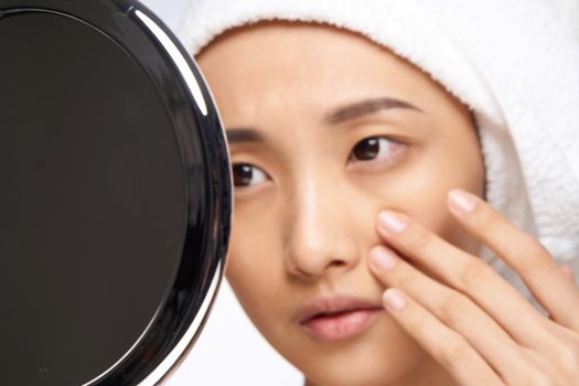woman of asian appearance touches her face with her hand and looks in the mirror clean skin. High quality photo
