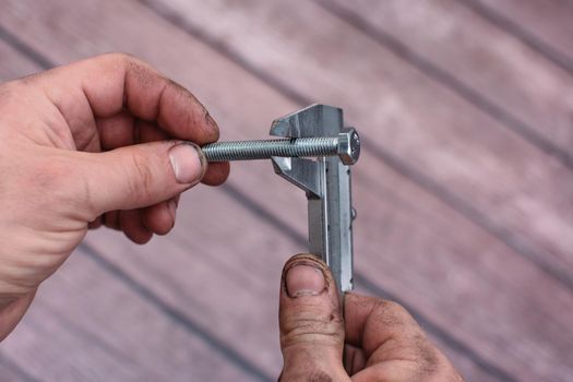 Vernier caliper and screw-bolt. Rough smeared working men's hands. close-up