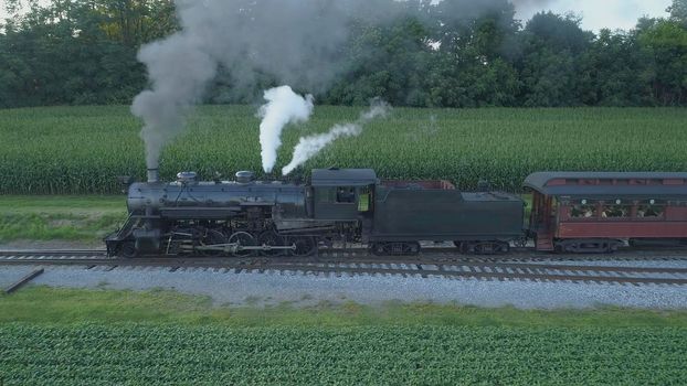 Aerial View of An Antique Restored Steam Locomotive Blowing Smoke and Steam Traveling Thru Farmlands and Countryside on a Sunny Summer Day