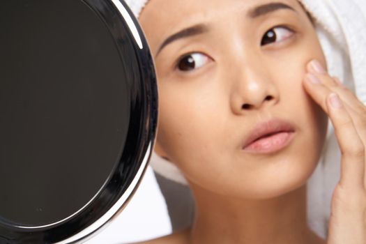 woman of asian appearance touches her face with her hand and looks in the mirror clean skin. High quality photo