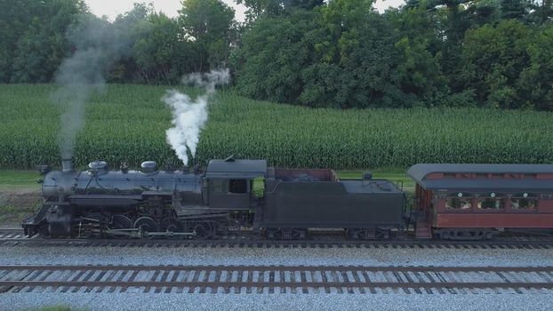 Aerial View of An Antique Restored Steam Locomotive Blowing Smoke and Steam Traveling Thru Farmlands and Countryside on a Sunny Summer Day