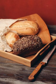 flour products rye bread on a tray and a sharp knife on a table on a red background. High quality photo