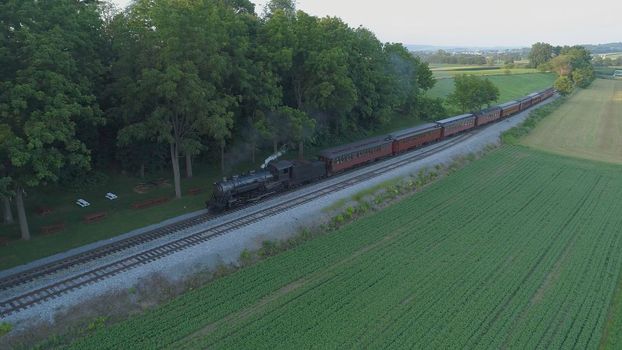 Aerial View of An Antique Restored Steam Locomotive Blowing Smoke and Steam Traveling Thru Farmlands and Countryside on a Sunny Summer Day