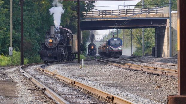 View of 3 Locomotives Spanning Over 100 Years 2 Steam and one Electric Passing Each Other Under a Bridge.